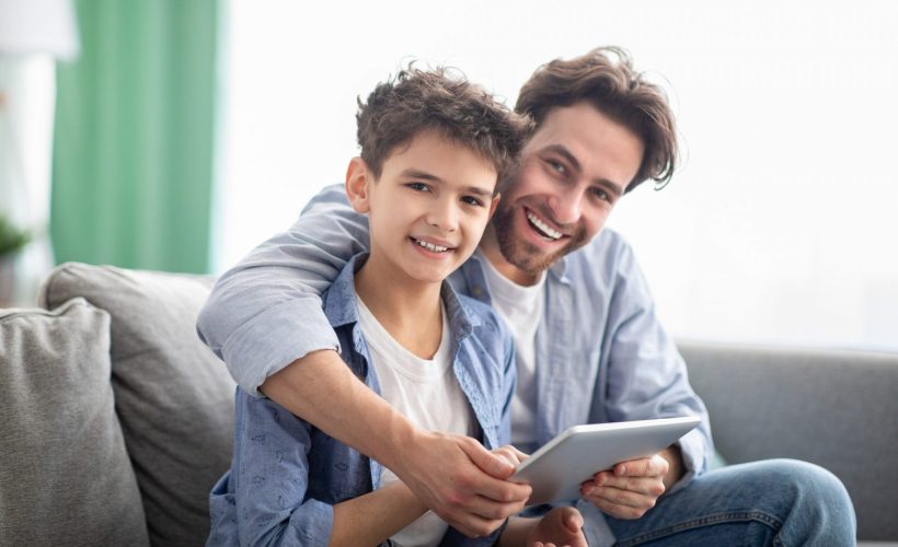 family-time-happy-dad-and-son-using-digital-tablet-browsing-internet-online-at-home-sitting-e1632233068896.jpg